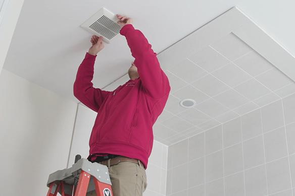 Man installing exhaust fan in bathroom