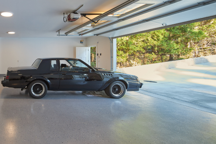 Vintage car parked in garage with shiny garage floor.
