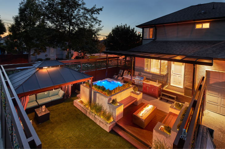 Glamourous outdoor backyard design featuring space with canopy, hot tub and fireplace.
