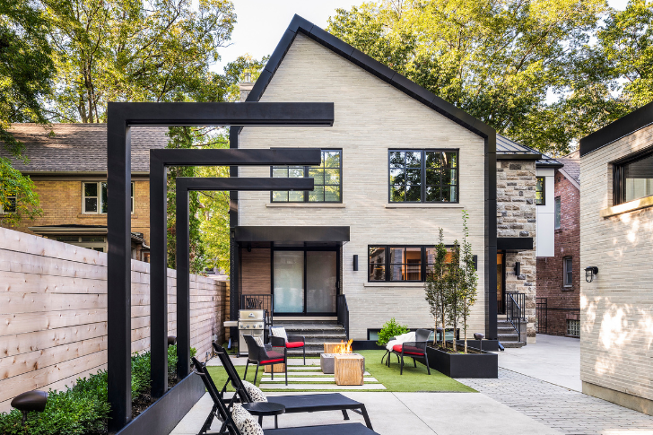 Stylish back exterior of home with modern sleek seating and fireplace.