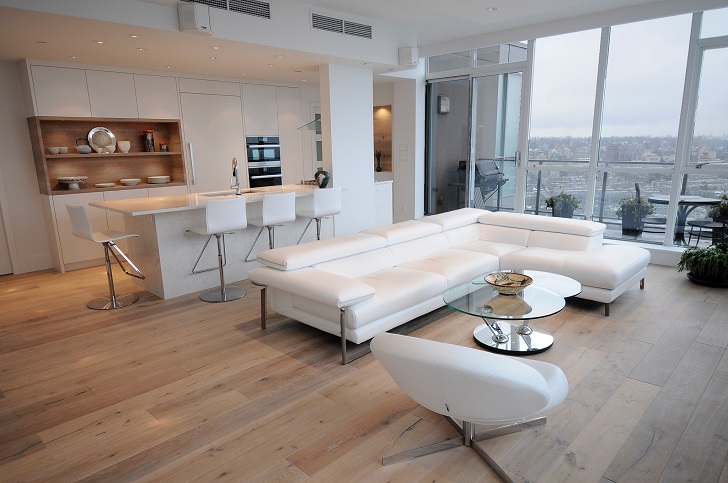 Beautiful and sleek condo renovation with large white couch and good view.