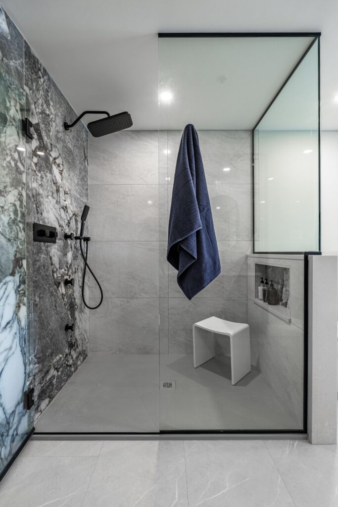 Feature tile wall with bronze veining connecting shower exhibit