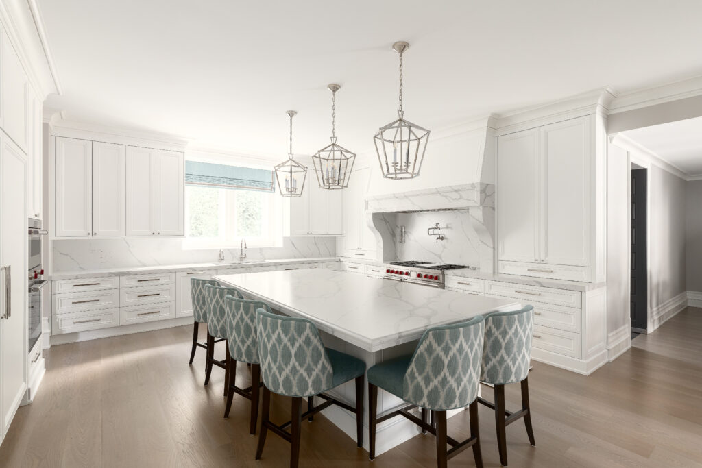 A modern white kitchen with marble countertops, an island with six blue-patterned chairs, three pendant lights above the island, and large windows letting in natural light.