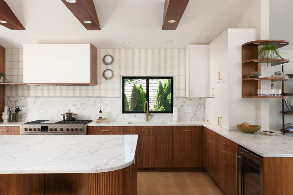 A kitchen with marble counter tops and white cabinets.