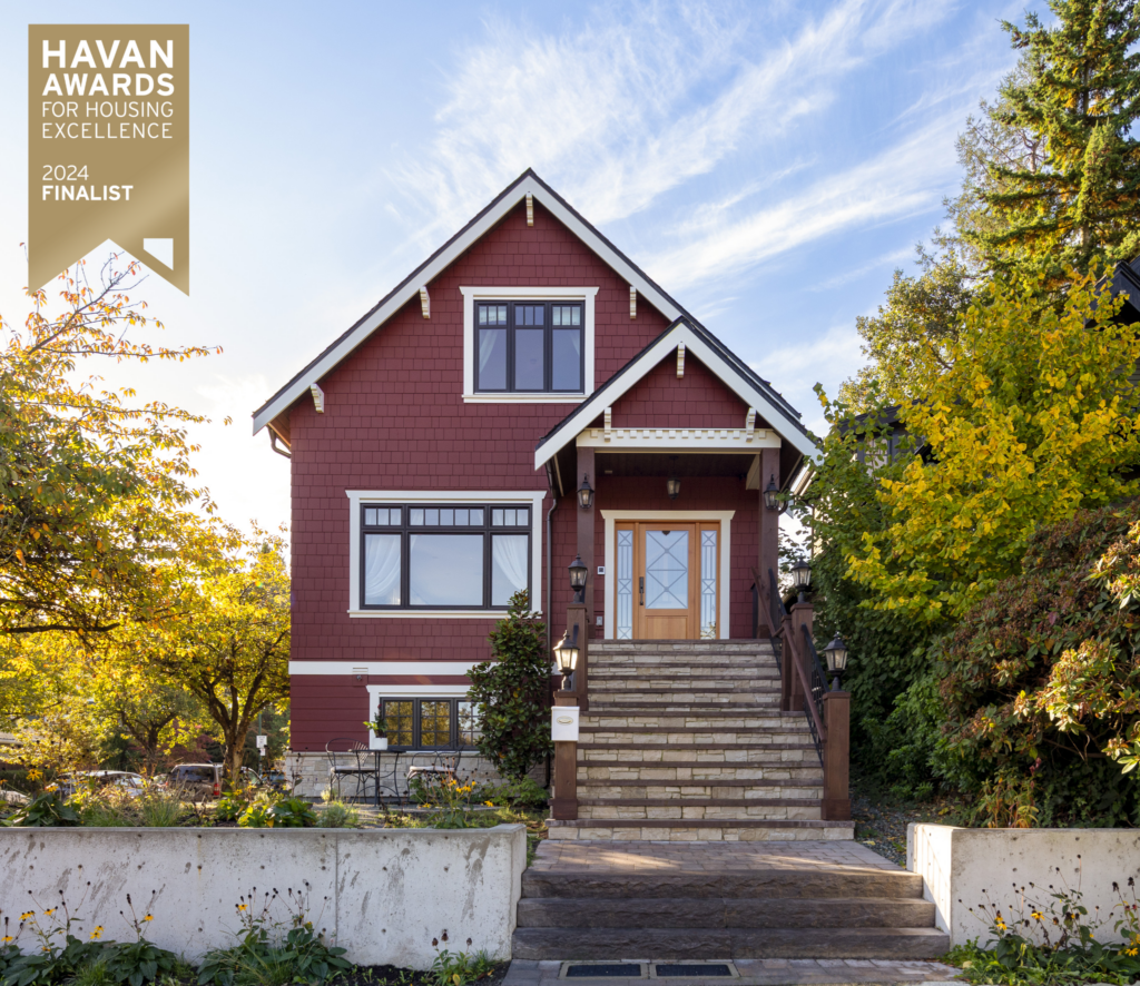 A red, two-story house with white trim and a large wooden front door is framed by lush trees. A gold HAVAN Awards for Housing Excellence 2024 Finalist badge is displayed in the top left corner.