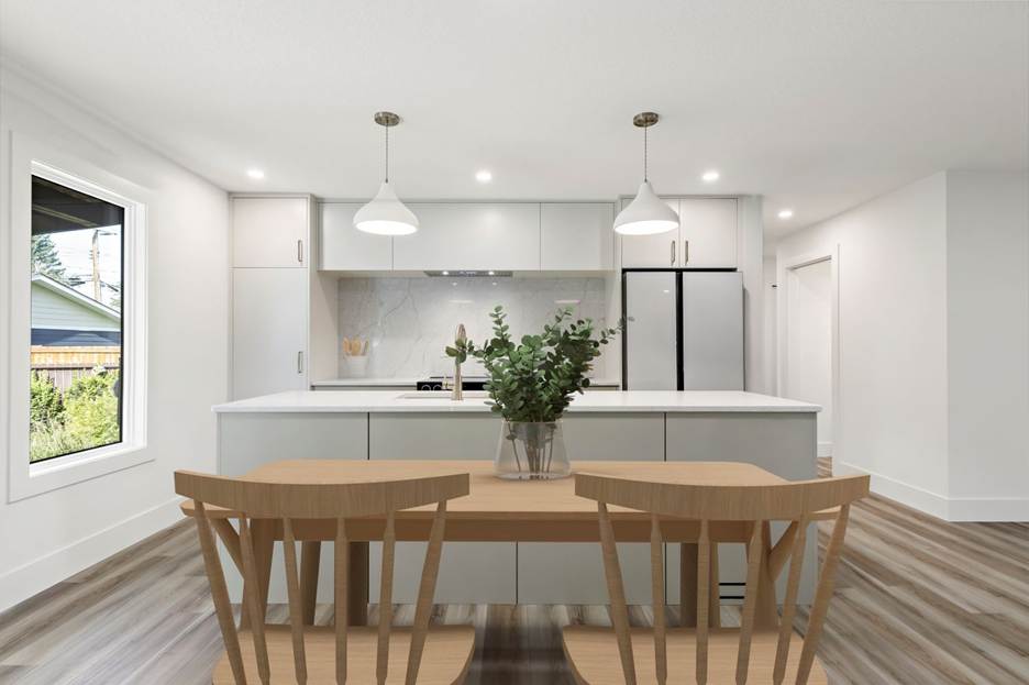 Modern kitchen with white cabinets, a marble backsplash, pendant lights, and stainless steel appliances. A wooden table with two chairs and a vase of greenery sits in the foreground. Large window on the left.